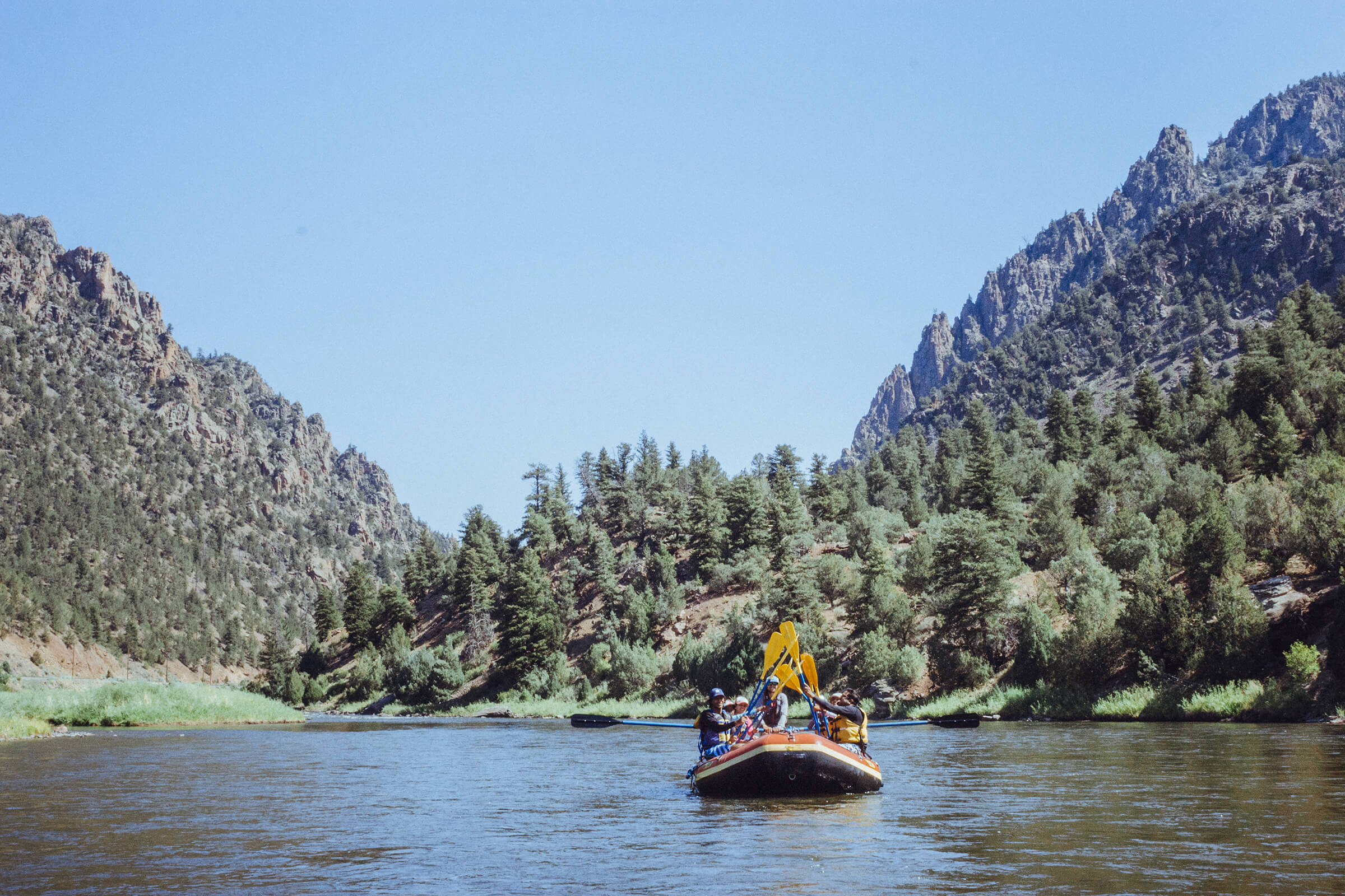 A group of rafters high fiving paddles while on the Colorado River in the summer