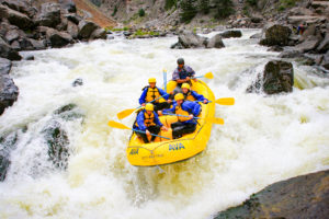 A group of rafters going over a drop in the Gore Canyon with whitewater surrounding them