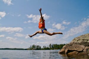 Woman jumping from rock wearing life jacket