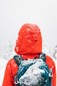 woman wearing insulated jacket and backpack with dusting of snow