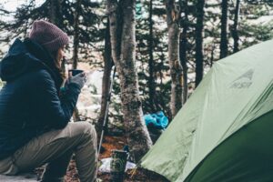 woman sipping warm beverage outside tent