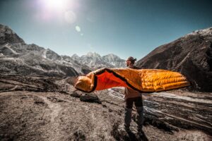 man airing out sleeping bag in mountains