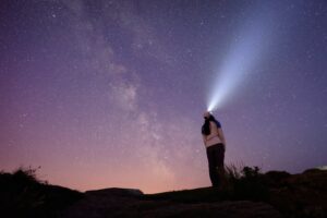 woman staring into stars with headlamp