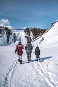 family walking through snow toward waterfall